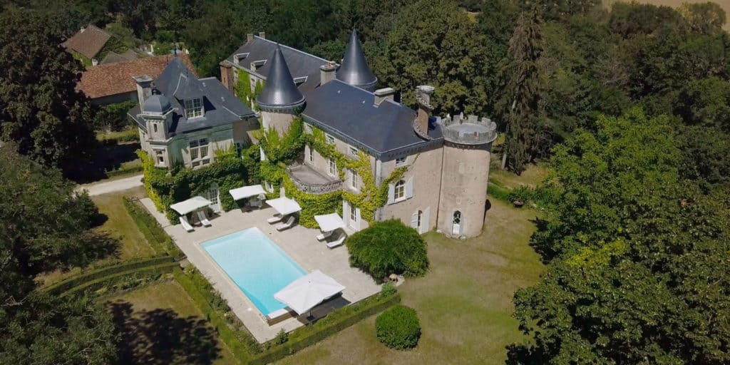 Survol d'un château et de son parc arboré avec piscine, tourisme