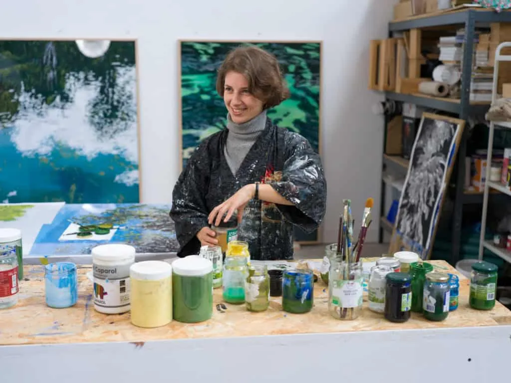 Clémentine Chalançon dans son atelier, entre ses toiles et ses pots de peinture, portrait Allow.art