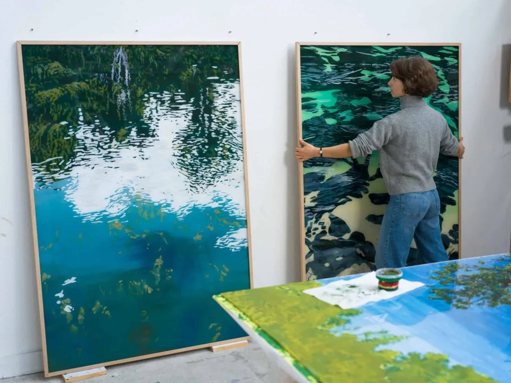 Clémentine Chalançon installant une toile de rivière contre le mur de son atelier, portrait Allow.art