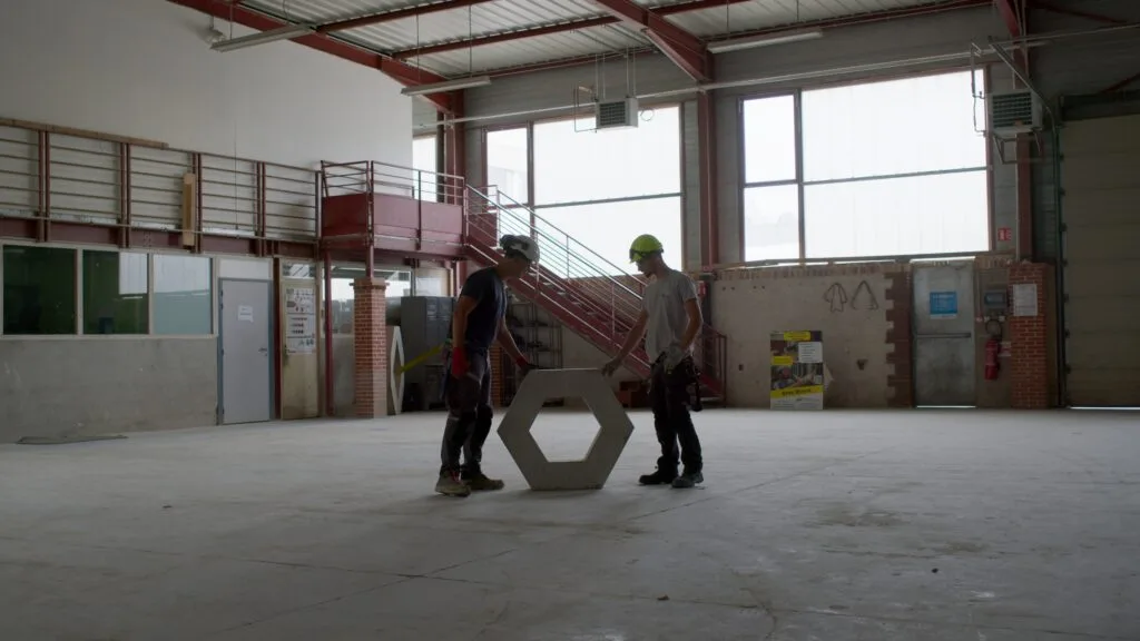 Deux apprentis maçons manipulent un élément en béton — BTP CFA de l'Ain
