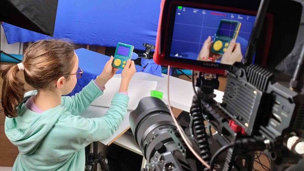 Équipe Pioucube en tournage studio : une enfant manipule le baladeur FLAM devant la caméra, coulisses des teasers Lunii